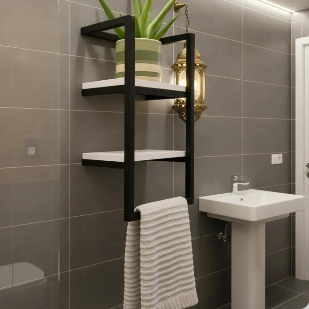 Étagère murale de salle de bain au style industriel en métal noir avec deux tablettes blanches, décorée d'une plante verte et d'une lanterne orientale, incluant un porte-serviette intégré.