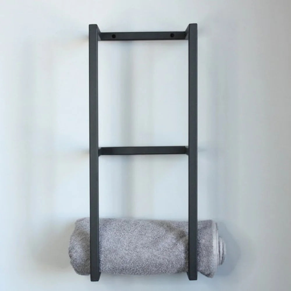 Vue de face d'un support à serviettes design en forme de double cadre noir, fixé sur un mur blanc épuré.