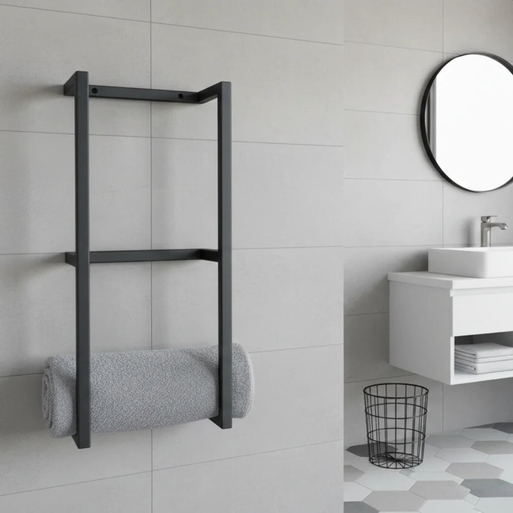 Support à serviettes mural en métal noir avec une serviette grise roulée, dans une salle de bain moderne avec carrelage gris clair.